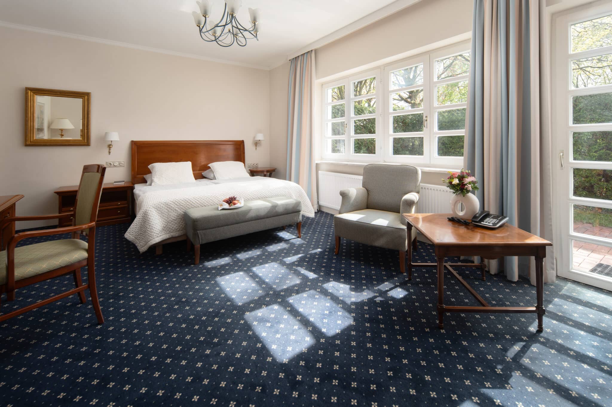 Hotelzimmer mit großzügiger Fenster Seite, blauem Teppichboden und Möbeln aus Holz