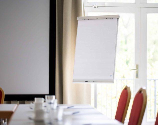 Flipchart im Alsterraum, im Vordergrund sind Tische und Stühle zu erkennen