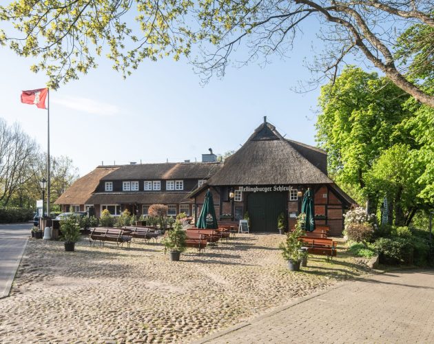 Aussenansicht des Hotels Mellingburger Schleuse mit grünen Bäumen und blauem Himmel